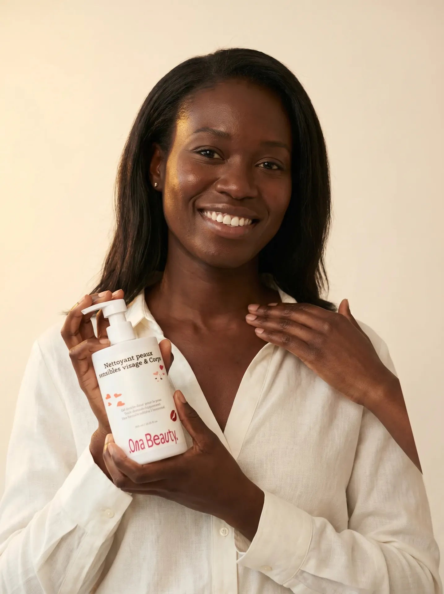 Amara tient le soin nettoyant hydratant visage et corps Ona Beauty, sourire lumineux